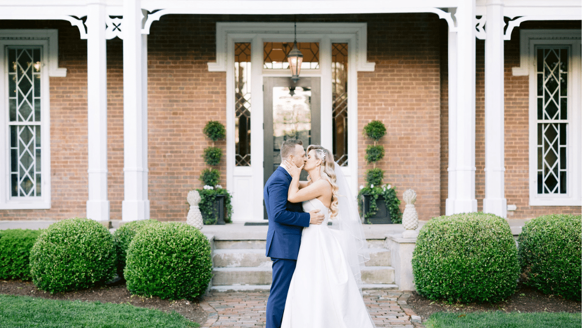 Bride & Groom kissing in front of Warrenwood Manor, a historic Kentucky wedding venue