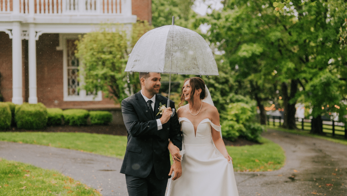 Bride and groom at Warrenwood Manor walking in the rain with an umbrella